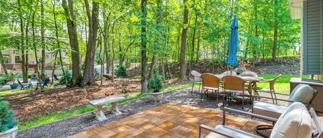 An outdoor patio area with a wooden deck, seating, and a table.