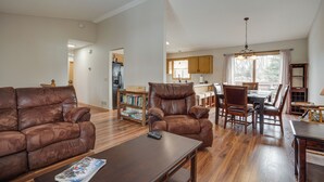 A spacious living room with a leather sofa, a wooden coffee table, and a dining area with wooden chairs and a table. - Sporty Blaine Home w/ Games ~ 2 Mi to Super Rink! (Blaine)