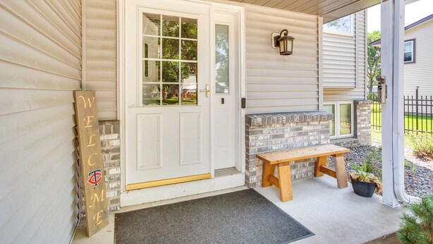 A front porch with a white door, a welcome sign, a bench, and a stone fireplace. - Sporty Blaine Home w/ Games ~ 2 Mi to Super Rink! (Blaine)