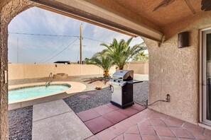 A pool with a hot tub, a barbecue grill, and a palm tree in a covered outdoor area.