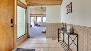 A wooden door leading to a room with a tiled floor, a bench, and a table with a lantern. - Nampa Vacation Rental Townhome Near Lake Lowell! (Nampa)