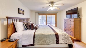 A bedroom with a bed, wooden headboard, a ceiling fan, a dresser, and a television. - Nampa Vacation Rental Townhome Near Lake Lowell! (Nampa)