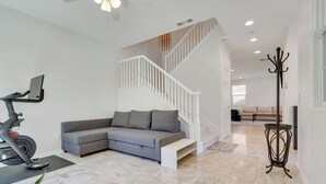 A spacious living area with a grey sectional sofa, a stationary bike, and a staircase. - Family-friendly Camarillo Home w/ Access to Pools! (Camarillo)