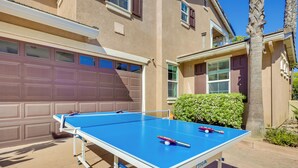 An outdoor ping pong table in front of a house with a garage and a palm tree. - Family-friendly Camarillo Home w/ Access to Pools! (Camarillo)