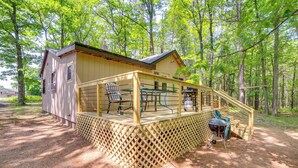 A wooden cabin with a deck, outdoor seating, and a grill. - Sunroom, Deck & Grills: Marquette Cottage! (Marquette)