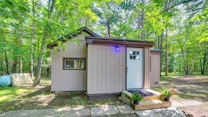 A small wooden cabin with a front door, a small window, and a porch with steps. - Sunroom, Deck & Grills: Marquette Cottage! (Marquette)