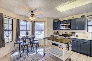 Une cuisine moderne avec des meubles de couleur sombre, un îlot central et un ventilateur de plafond.