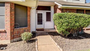 A two-story residential building with a brick facade, a front door, and a small front yard with a concrete pathway and a bush. - 4 Mi to Joe Pool Lake: Home in Grand Prairie (Grand Prairie)