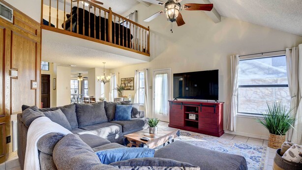 A spacious living room with a large sectional sofa, a wooden staircase, a ceiling fan, and a television. - 4 Mi to Joe Pool Lake: Home in Grand Prairie (Grand Prairie)