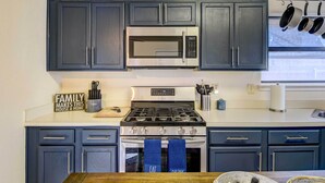 A kitchen with dark cabinets, a stainless steel microwave, a gas stove, and a coffee sign. - 4 Mi to Joe Pool Lake: Home in Grand Prairie (Grand Prairie)