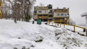 Un immeuble à plusieurs étages, doté de balcons et dont le sol est recouvert de neige.