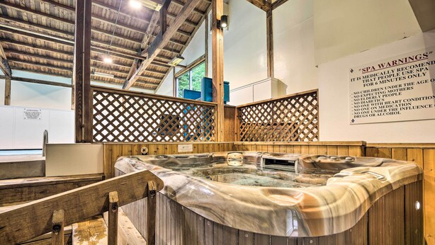 Un espace bien-être doté d’un bain à remous en bois, d’un plafond en bois et d’un panneau indiquant les consignes de sécurité à respecter dans le spa.