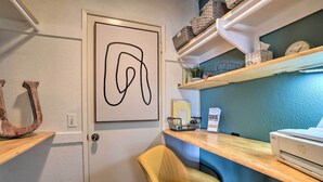 A reception area with a wooden desk, a chair, a framed abstract artwork, a horse sculpture, and a printer.