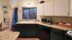 A kitchen with granite countertops, a sink, a microwave, and black cabinets.