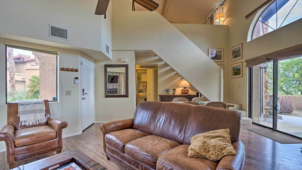 A spacious living room with a leather sofa, a coffee table, and a chair. A staircase leads to an upper level.