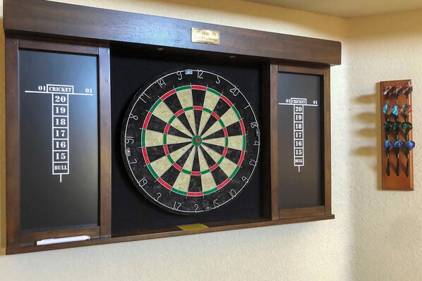 A dartboard mounted on a wall with a dartboard case and a small plaque above it.