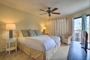 A bedroom with a bed, bedside lamps, a ceiling fan, a chair, a desk, and a window with curtains. - Borrego Springs Retreat w/ Grill & Patio! (Borrego Springs)