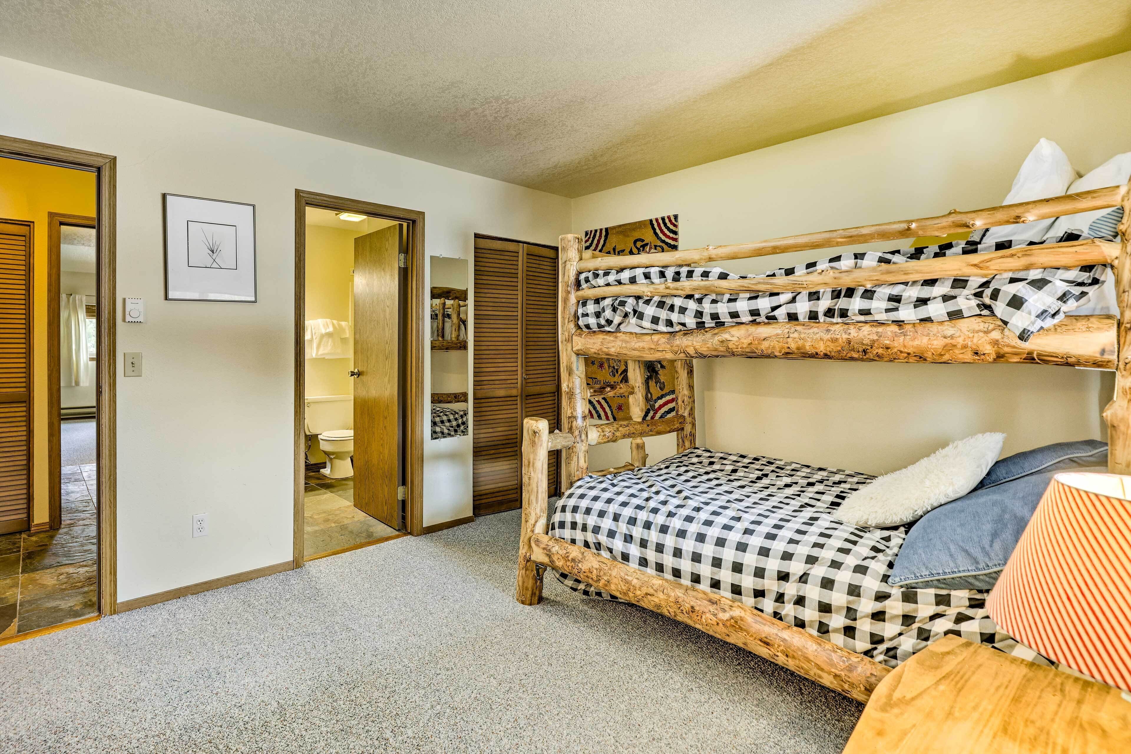 A bunk bed with checkered bedding, a wooden headboard, and a lamp on the side.