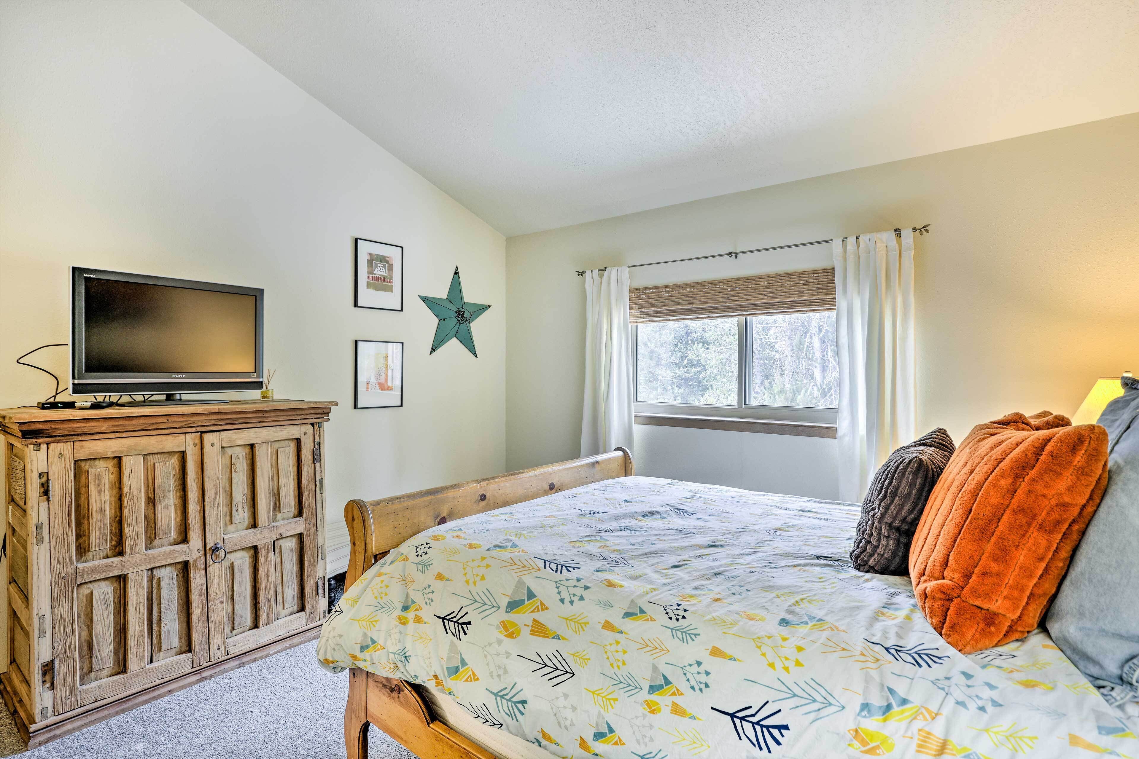 Une chambre à coucher avec un lit, une armoire en bois, un téléviseur et une fenêtre avec des rideaux.