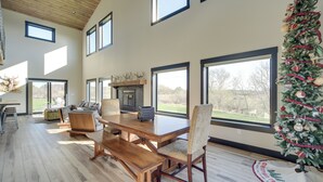 A spacious dining area with a large wooden table and chairs, large windows, and a decorated Christmas tree. - Large Home w/ Land in Prairie Farm! (Prairie Farm)