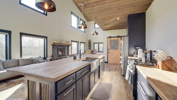 A spacious kitchen with a large island, wooden ceiling, and ample natural light from large windows. - Large Home w/ Land in Prairie Farm! (Prairie Farm)