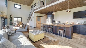 A spacious living area with a high ceiling, a large sofa, a wooden dining table, and a kitchen with modern appliances. - Large Home w/ Land in Prairie Farm! (Prairie Farm)