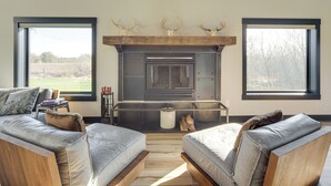 A modern living room with a fireplace, two sofas, and large windows. - Large Home w/ Land in Prairie Farm! (Prairie Farm)