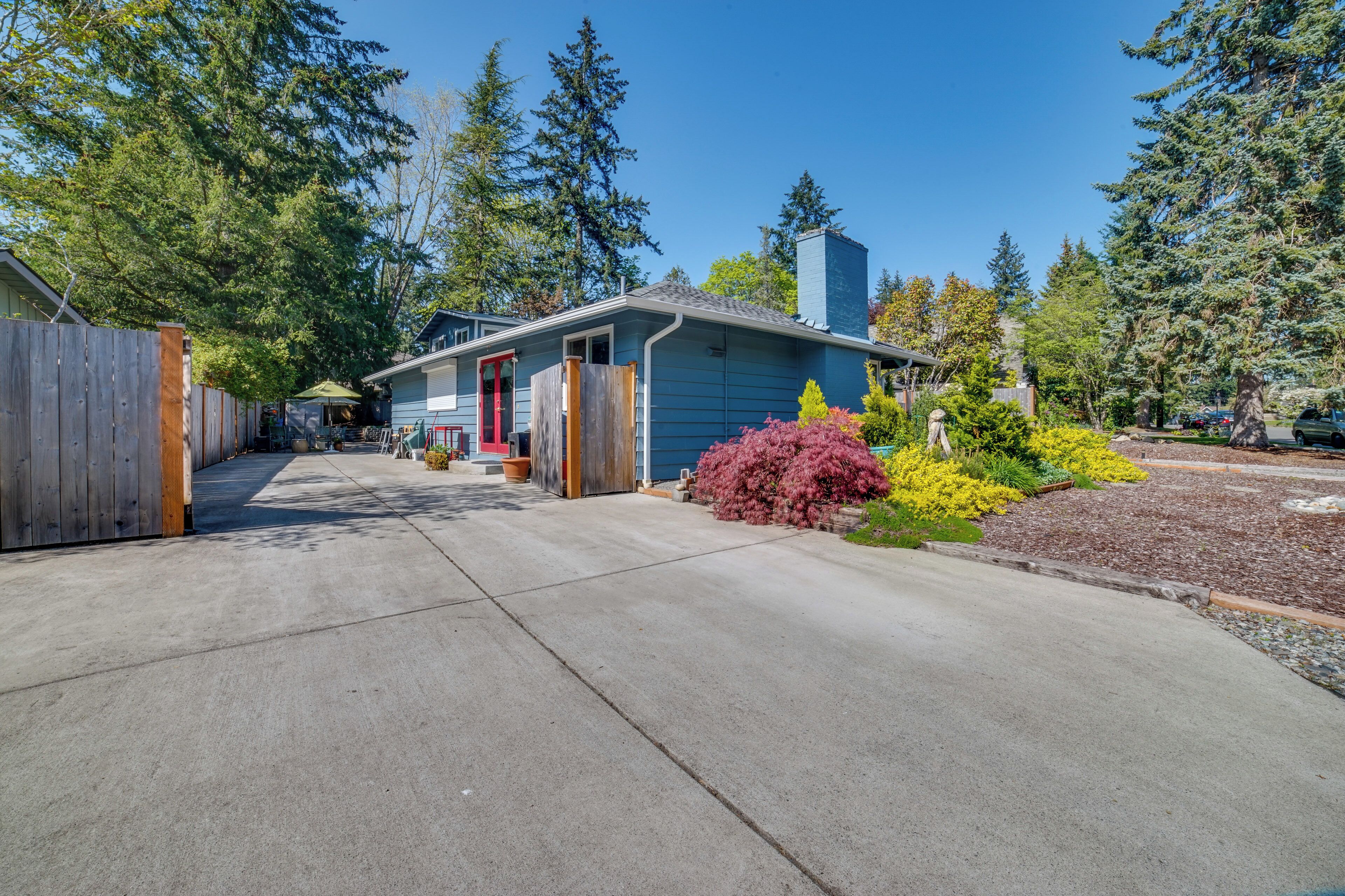 A residential house with a front yard, driveway, and a wooden fence.