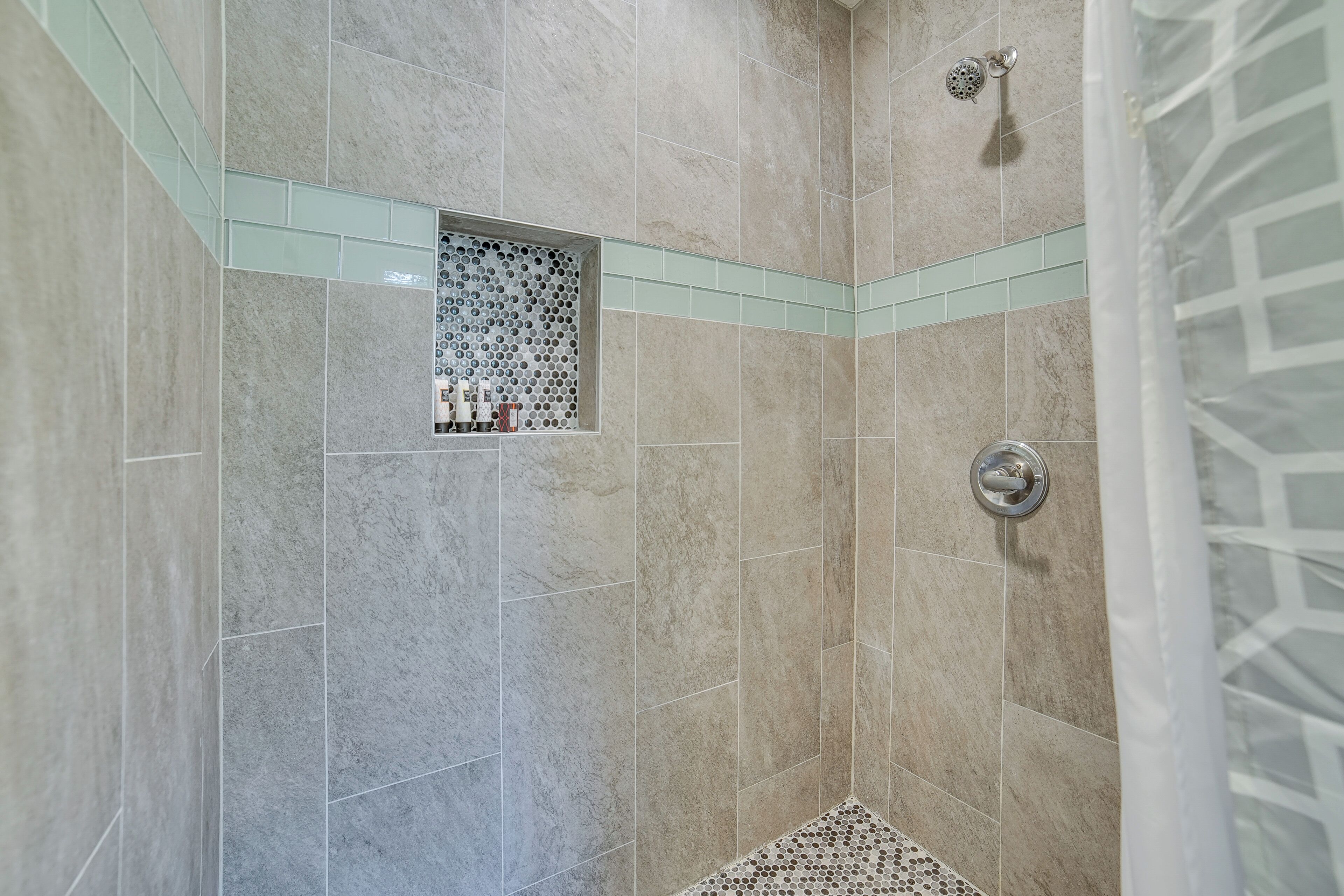 A shower with a glass partition and a showerhead.