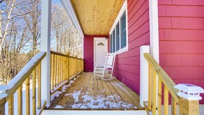 Une terrasse en bois avec une rambarde blanche, une porte en bois et une fenêtre.
