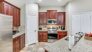 A kitchen with wooden cabinets, stainless steel appliances, granite countertops, and a tiled backsplash.
