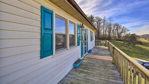 A wooden deck with a railing, a house with white siding and teal shutters, and a clear sky. - Pet-friendly Home w/ Grill & Farm in Meadowview! (Meadowview)