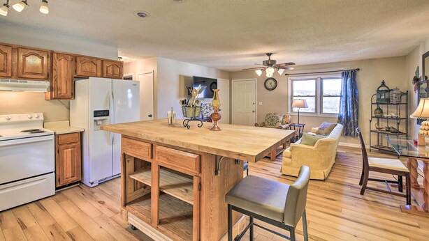 A spacious kitchen with wooden cabinets, a large island, and a dining area with a glass table and chairs. - Pet-friendly Home w/ Grill & Farm in Meadowview! (Meadowview)