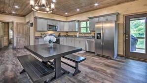 A modern kitchen with a central island, stainless steel appliances, and a wooden ceiling.