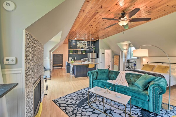 Un loft spacieux avec de hauts plafonds, un canapé confortable de couleur turquoise, une cuisine moderne et un coin repas.