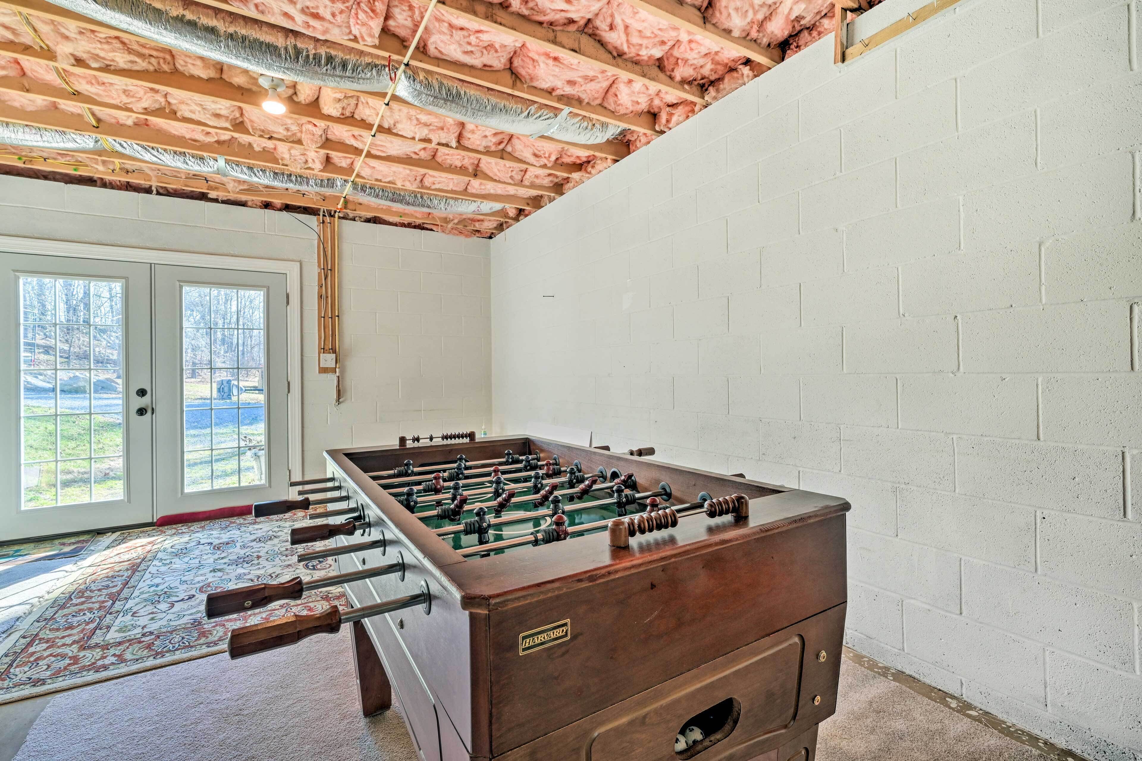A room with a foosball table, a patterned rug, and a view through a glass door to an outdoor area.