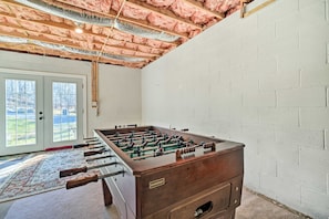 A room with a foosball table, a patterned rug, and a view through a glass door to an outdoor area. - Berkeley Springs Vacation Home w/ Fire Pit! (Berkeley Springs)