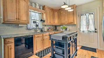 A kitchen with wooden cabinets, a black countertop, and a black island with baskets.