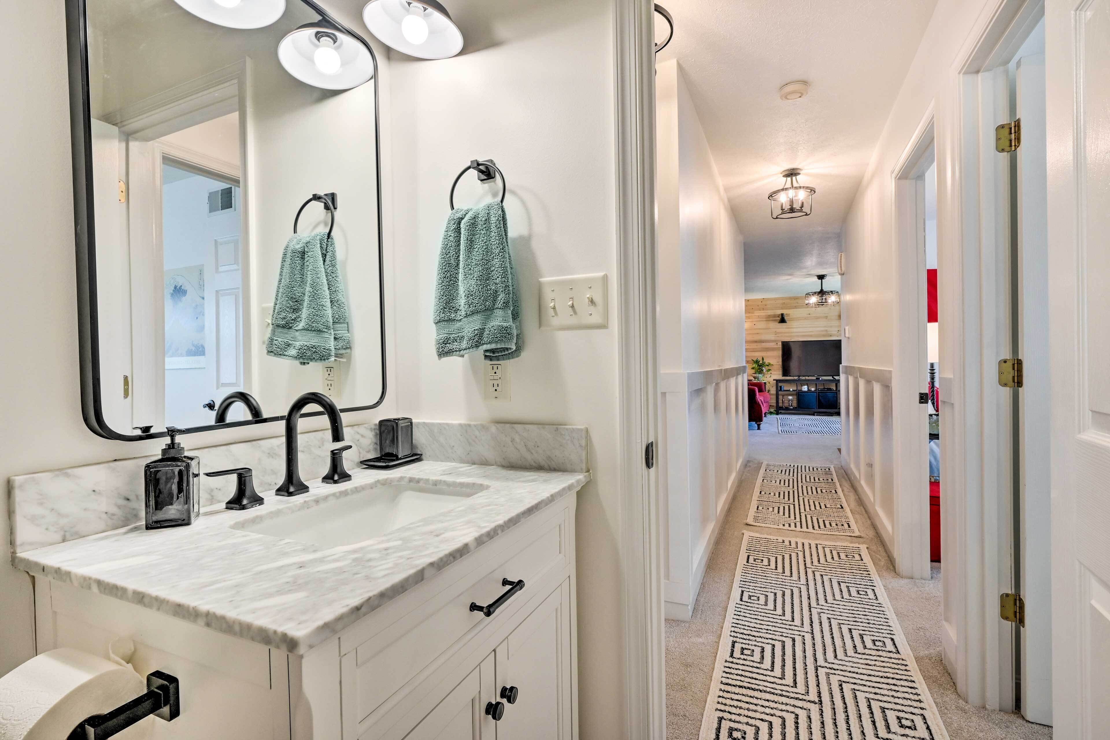 A modern bathroom with a large mirror, two sinks, and a towel rack.