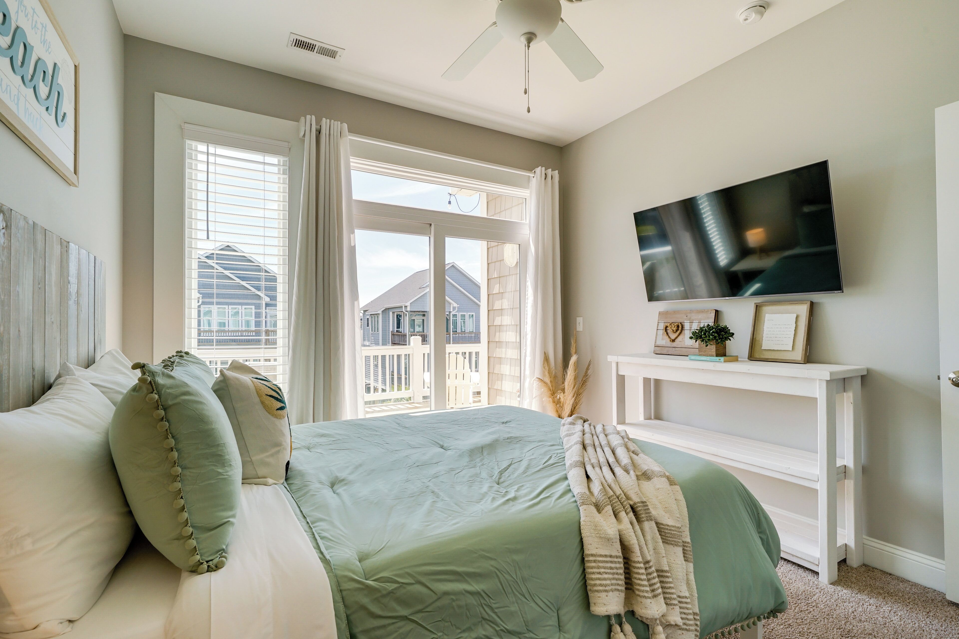 A bedroom with a bed, a TV, a window with curtains, and a view of buildings outside.