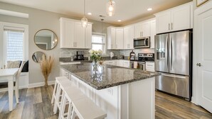 A modern kitchen with white cabinets, stainless steel appliances, and a granite countertop. - Modern Surf City Beach House w/ Hot Tub! (Holly Ridge)