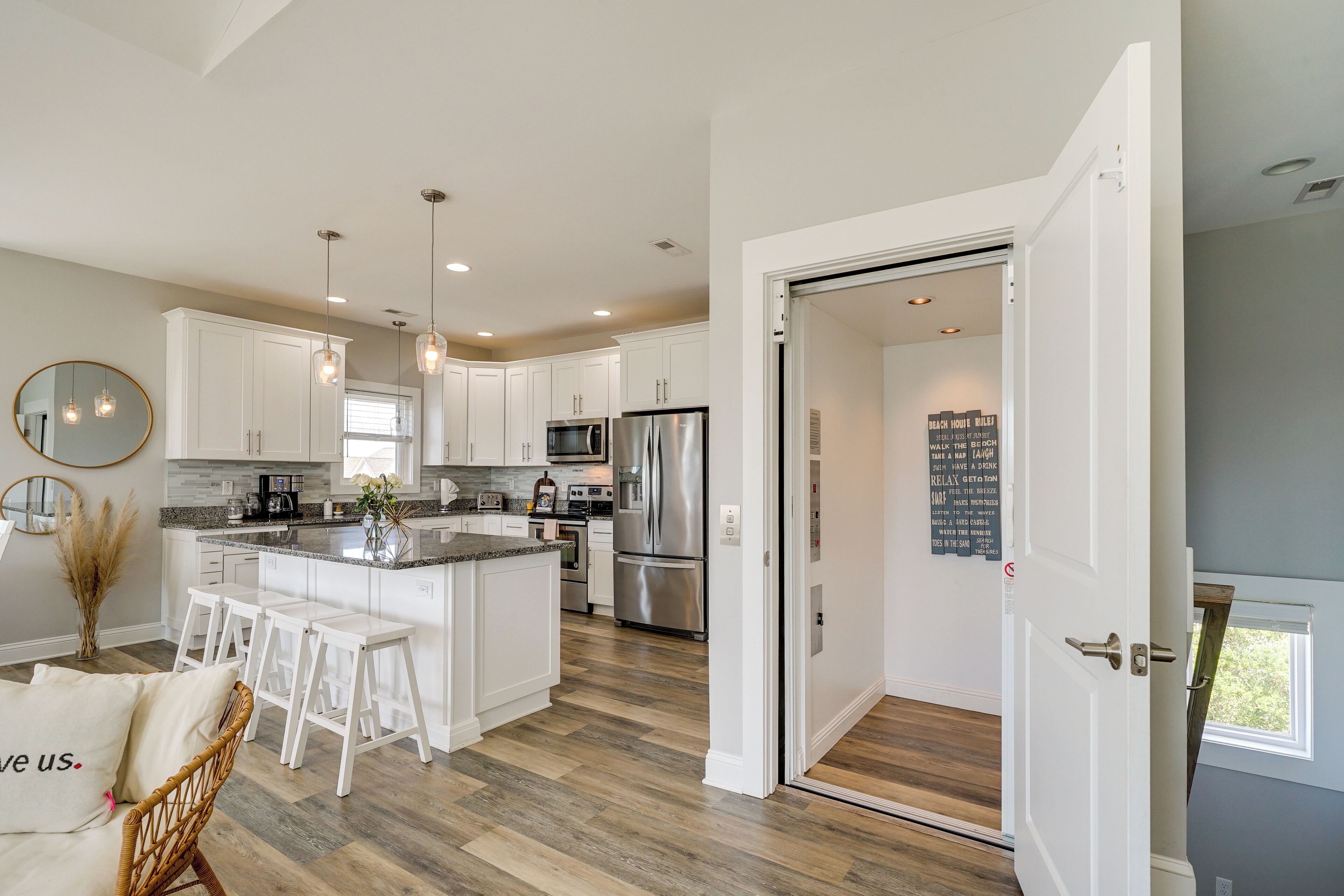 A modern kitchen with white cabinets, stainless steel appliances, and a central island with bar stools.