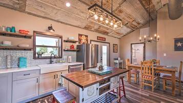 A rustic kitchen with a wooden island, stainless steel appliances, and a farmhouse-style dining area.