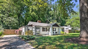 A two-story house with a front porch, a driveway, and a large tree in the yard.