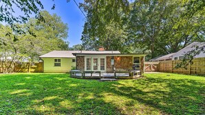 A house with a fenced backyard, a porch with benches, and a small deck.