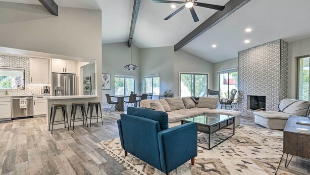 A spacious living area with a large sofa, a coffee table, and a TV. There is a kitchen area with a refrigerator and a dining table. The room has a high ceiling with exposed beams and a ceiling fan. - Dog-friendly Scottsdale Retreat w/ Private Pool! (Scottsdale)