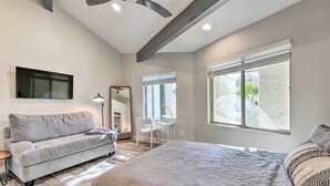 A modern bedroom with a large bed, a grey sofa, a desk, and a ceiling fan. - Dog-friendly Scottsdale Retreat w/ Private Pool! (Scottsdale)