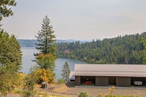 Une cabane avec un garage et une vue sur un lac entouré de forêt.