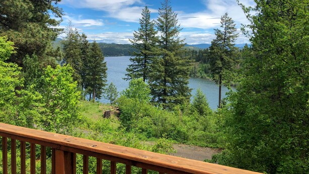 Eine Holzterrasse mit Blick auf einen See, der von dichtem Wald umgeben ist.