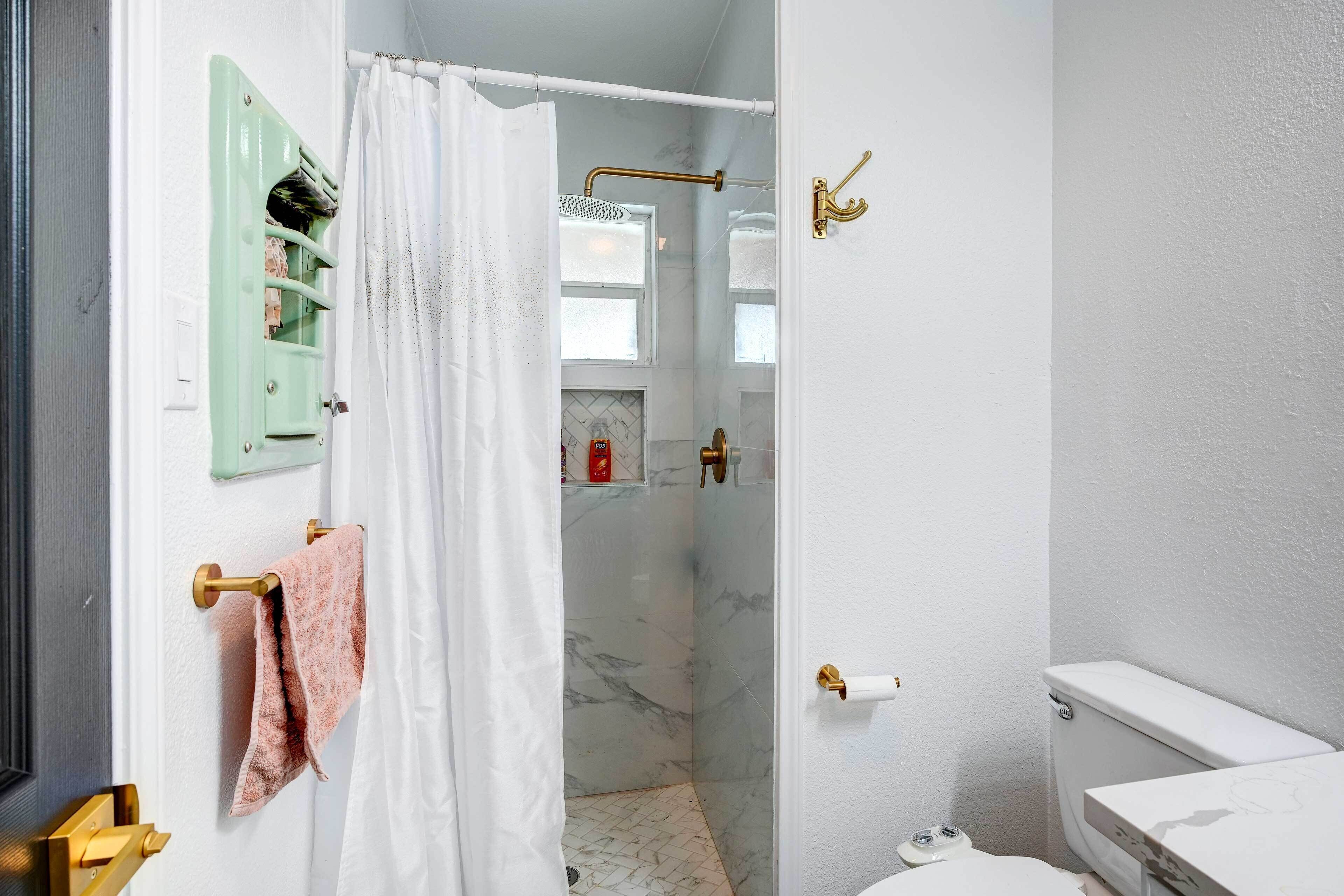 A bathroom with a shower, toilet, and a towel rack.